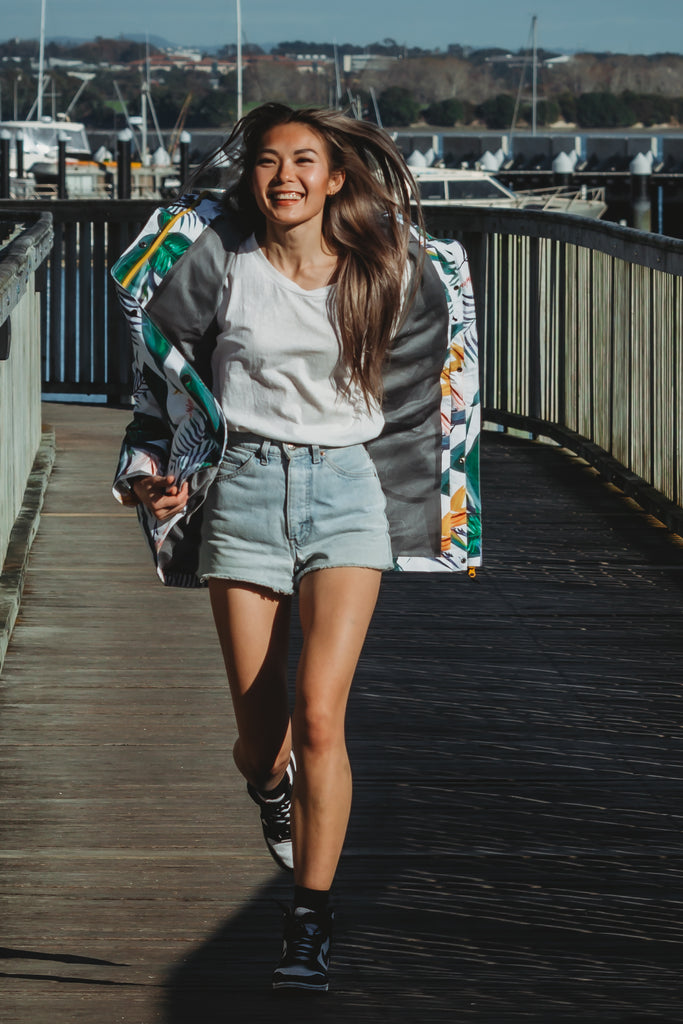 Scribbler rainwear, waterproof raincoat for women, rain jacket for ladies, outerwear, waterproof, mesh lined, lightweight, recycled plastic, sustainable fashion, winter coat, tropical Tropic print, mesh lined, beautiful, colourful print, breathable, packable coat, NZ, New Zealand designer, plus size, curvy, curves, white, green leaves, strelitzia, colourful rain jacket